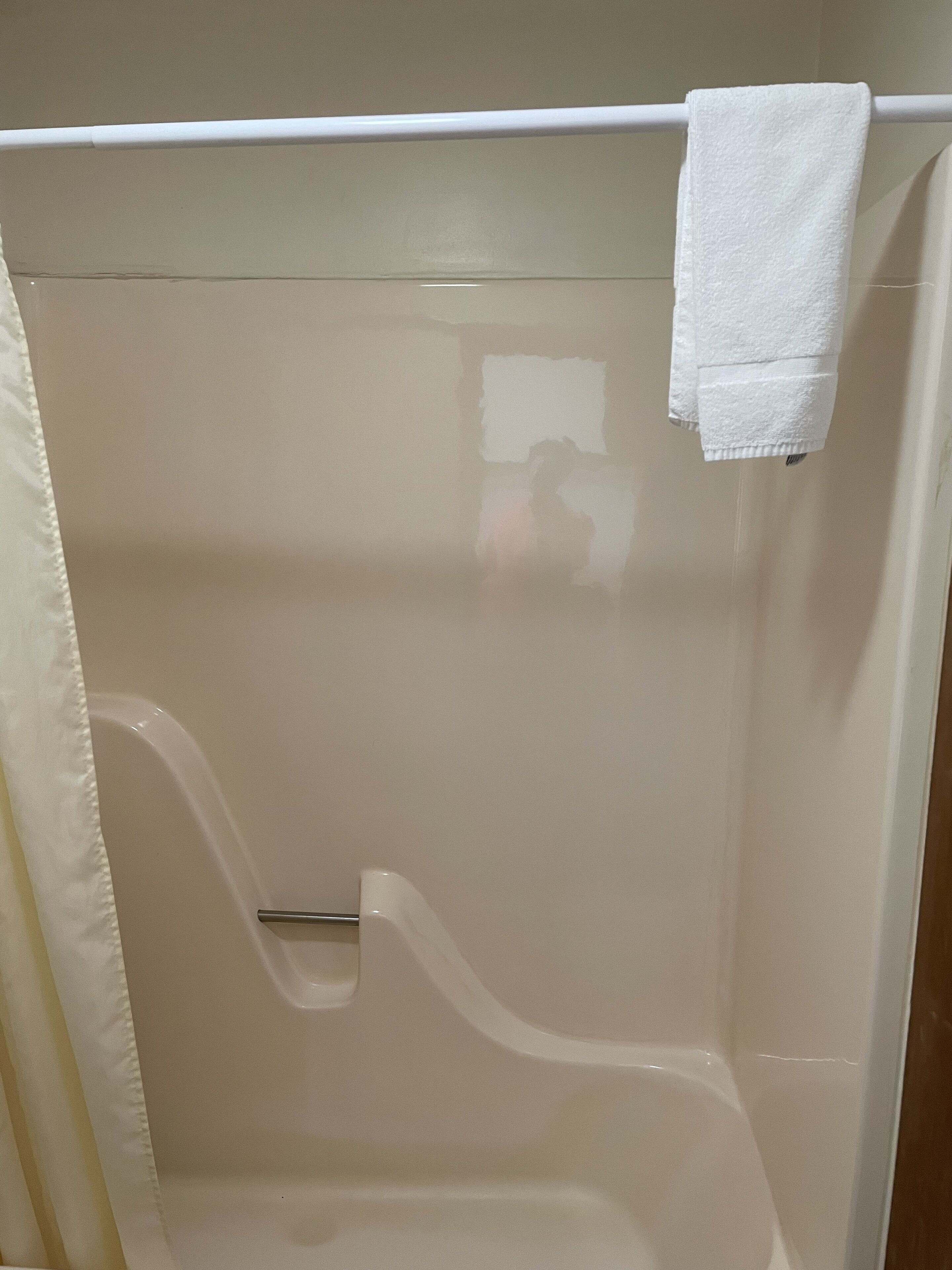 Un baño con una bañera, una cortina de ducha y una toalla colgada en la pared.