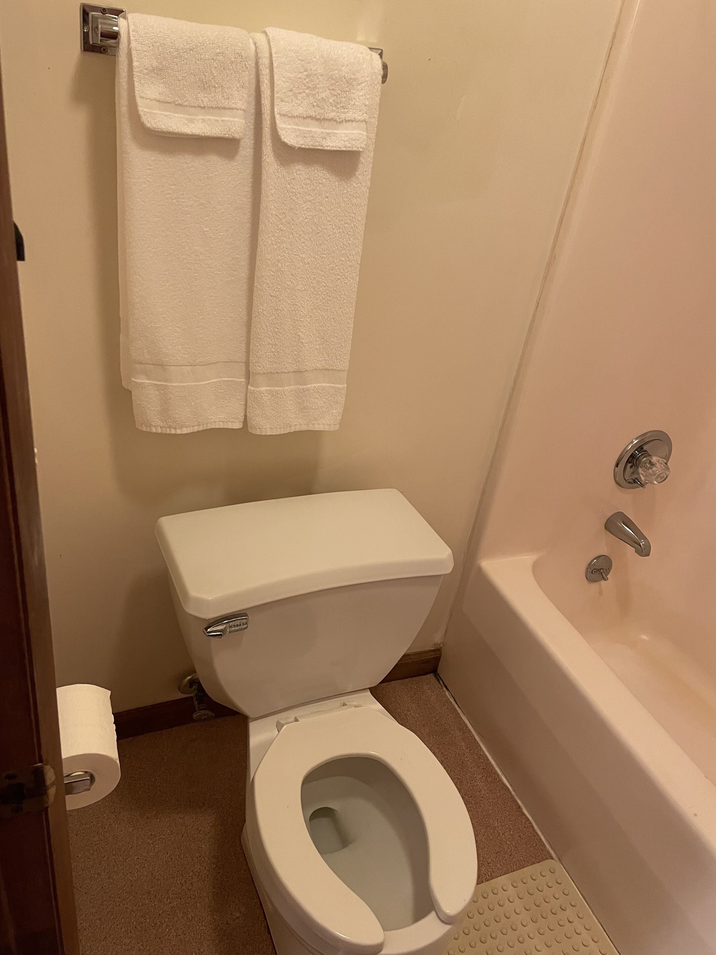 Une salle de bain équipée de toilettes, d’une baignoire et de deux serviettes accrochées au mur.