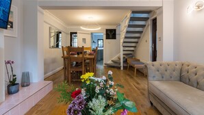 Un grand espace de vie comprenant un canapé, une table à manger avec des chaises et un escalier menant à un autre niveau.