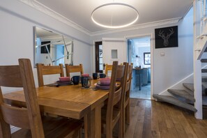 A dining area with a wooden table and chairs, a modern pendant light, and a black wall art piece.