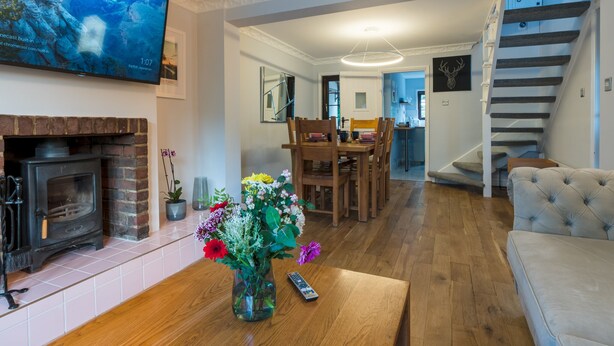 Un salon doté d’une cheminée, d’un téléviseur fixé au mur, d’un coin repas avec des meubles en bois et d’un escalier.