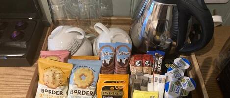 A kitchen counter with various food items, a kettle, and glasses.