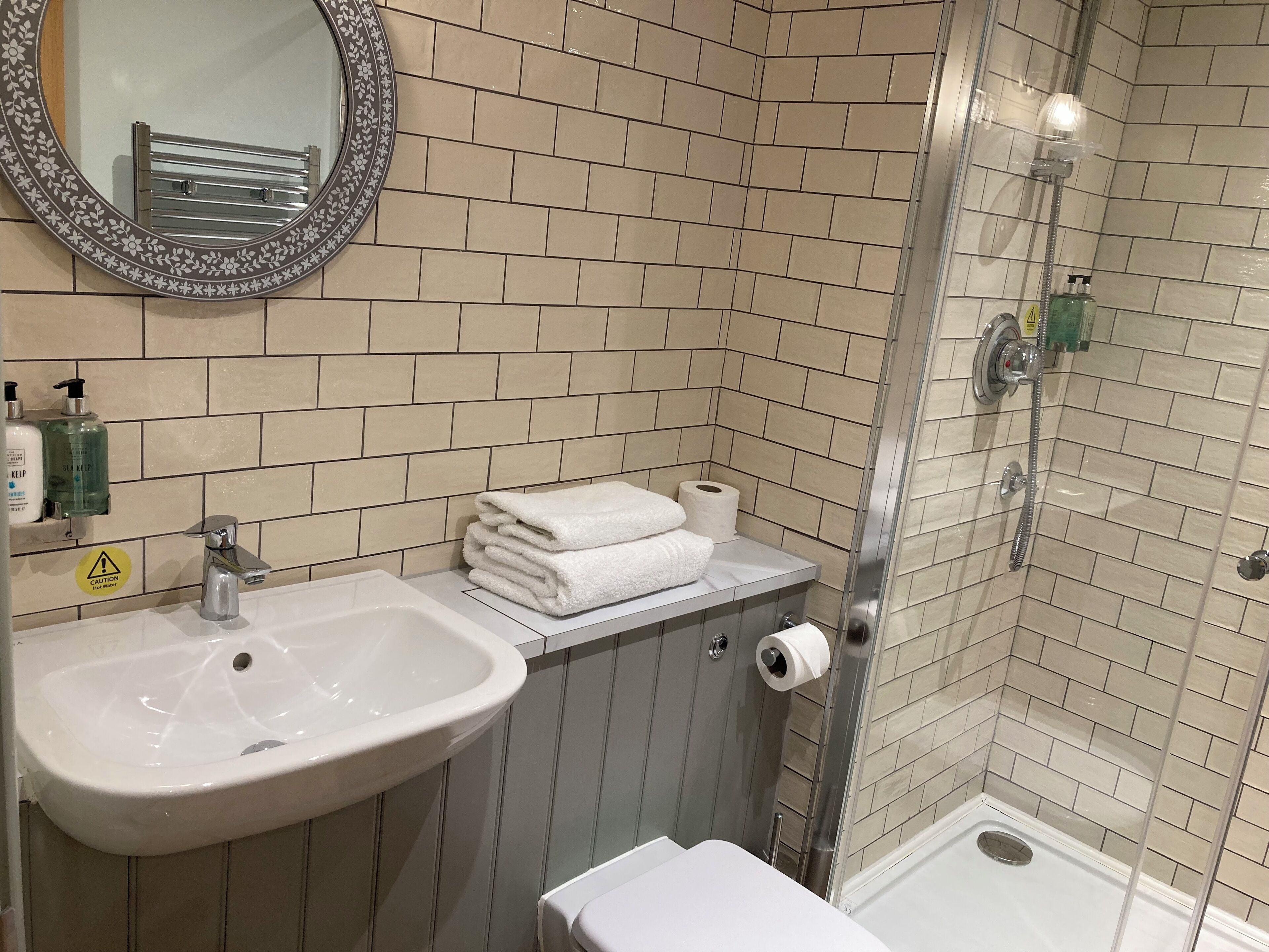 Een badkamer met een wastafel, spiegel, toilet en douche.