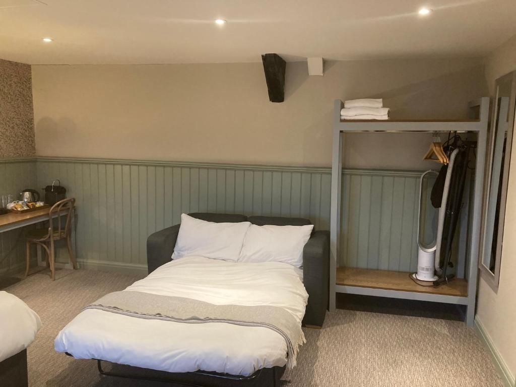 Una habitación de hotel con cama, escritorio, silla, armario y radiador.