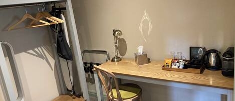 A bunk bed with a wooden desk, a chair, a lamp, a tissue box, a coffee maker, and a trash bin.