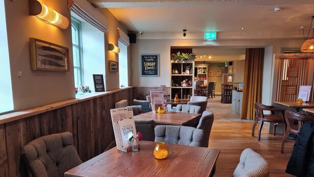Un restaurant avec des tables et des chaises en bois, un tableau affichant le menu et une pancarte indiquant que des plats de viande rôtie sont servis le dimanche.