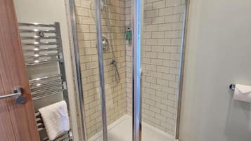 Ein modernes Badezimmer mit einer gläsernen Duschkabine, Holzboden und Toilette.