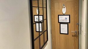 Une porte en bois sur laquelle est apposée une pancarte indiquant « Veuillez ne pas déranger », et à laquelle sont fixés deux documents encadrés.