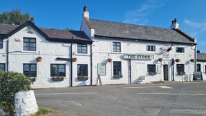 Un bâtiment blanc avec une enseigne indiquant « The Stork » et un panneau publicitaire annonçant « Cask and Great Food Letting Rooms ».
