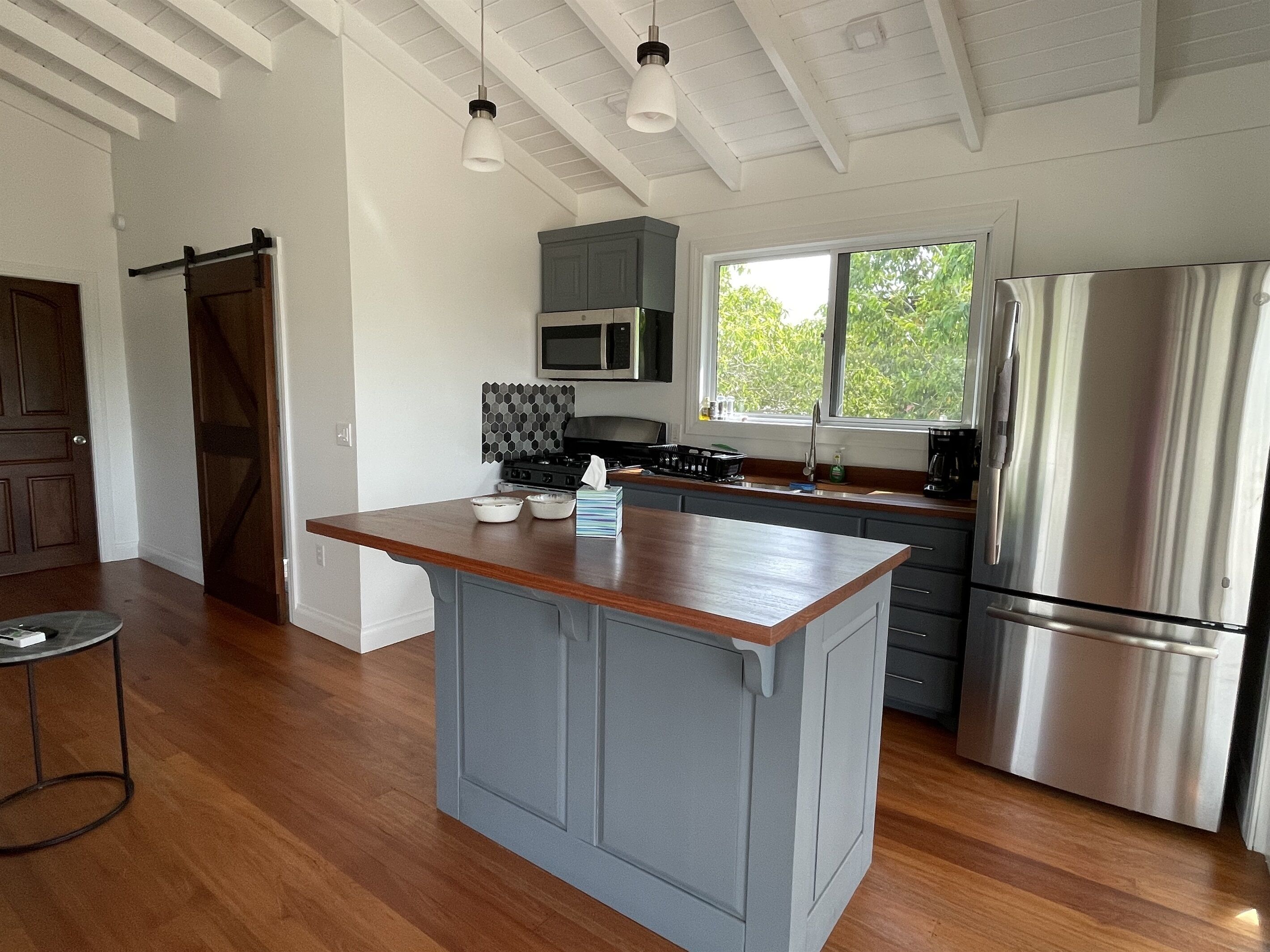 A modern kitchen with a central island, stainless steel appliances, and a large window providing natural light.