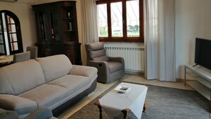 Een woonkamer met een bank, fauteuil en een tafel met een afstandsbediening.