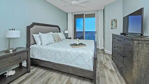 A bedroom with a bed, a nightstand, a dresser, a television, and a balcony with a view. - Newly remodeled and close to everything you need at Sea Glass Serenity.  (Navarre)