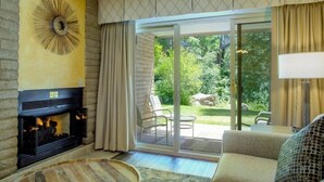 A living room with a fireplace, a sofa, and a view of a garden through a sliding glass door. - Sandstone Creek Spacious 1BR Condo w Pool (Vail)