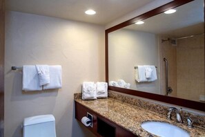 Ein Hotelbad mit einer Waschtischplatte aus Granit, einem Waschbecken, einem Spiegel und einer Toilette.