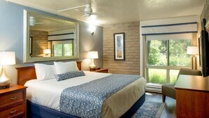A hotel room with a large bed, a ceiling fan, a window with a view of greenery, and a desk with a chair. - Bright & Sunny 2BR Condo with Jacuzzi & Tennis Court (Vail)