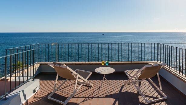 A balcony with two chairs and a small table, overlooking a body of water. - Cottage Pearl-Rural Holiday Experience by SeaPearl.. (Paul do Mar - Calheta)
