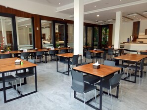 A modern dining area with wooden tables and black chairs, a reception desk, and a view of the interior. - Seventeen Hotel (Banda Aceh)