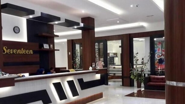 A hotel reception area with a modern design, a reception desk, and a visible clock.