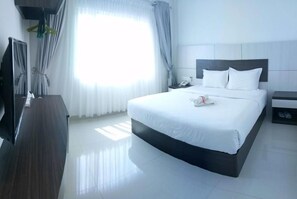A hotel room with a large bed, bedside tables, a TV, and a window with curtains. - Seventeen Hotel (Banda Aceh)