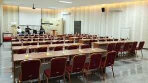 A conference room with multiple tables and chairs, a projector screen, and an air conditioning unit.