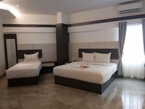 Une chambre d’hôtel avec deux lits, une table de chevet, un miroir et un appareil de climatisation.