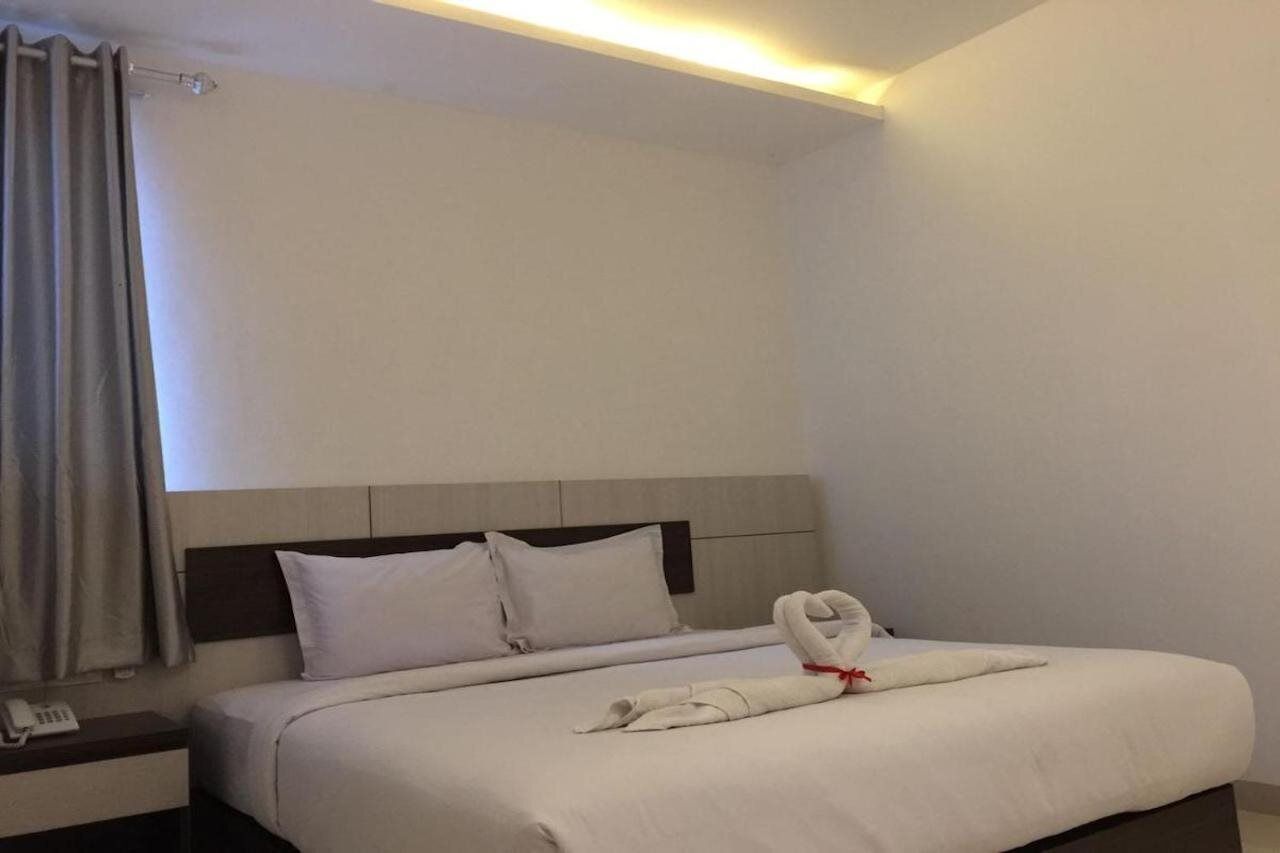 Een hotelkamer met een net opgemaakt bed, een bedtelefoon en een gordijn.