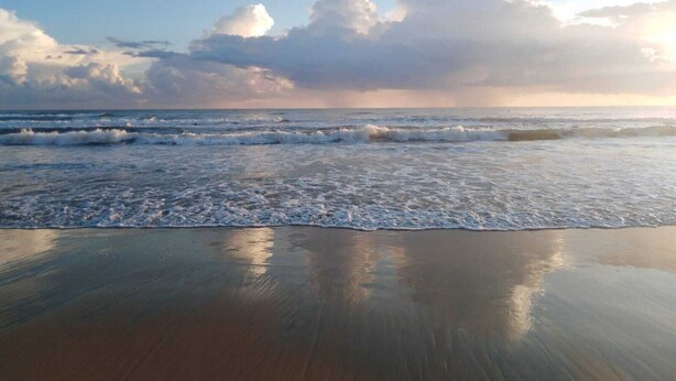 Een strand met golven en een heldere lucht.