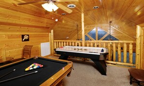 Relax in a room with a pool table, foosball table, and outdoor views from a sloped ceiling.