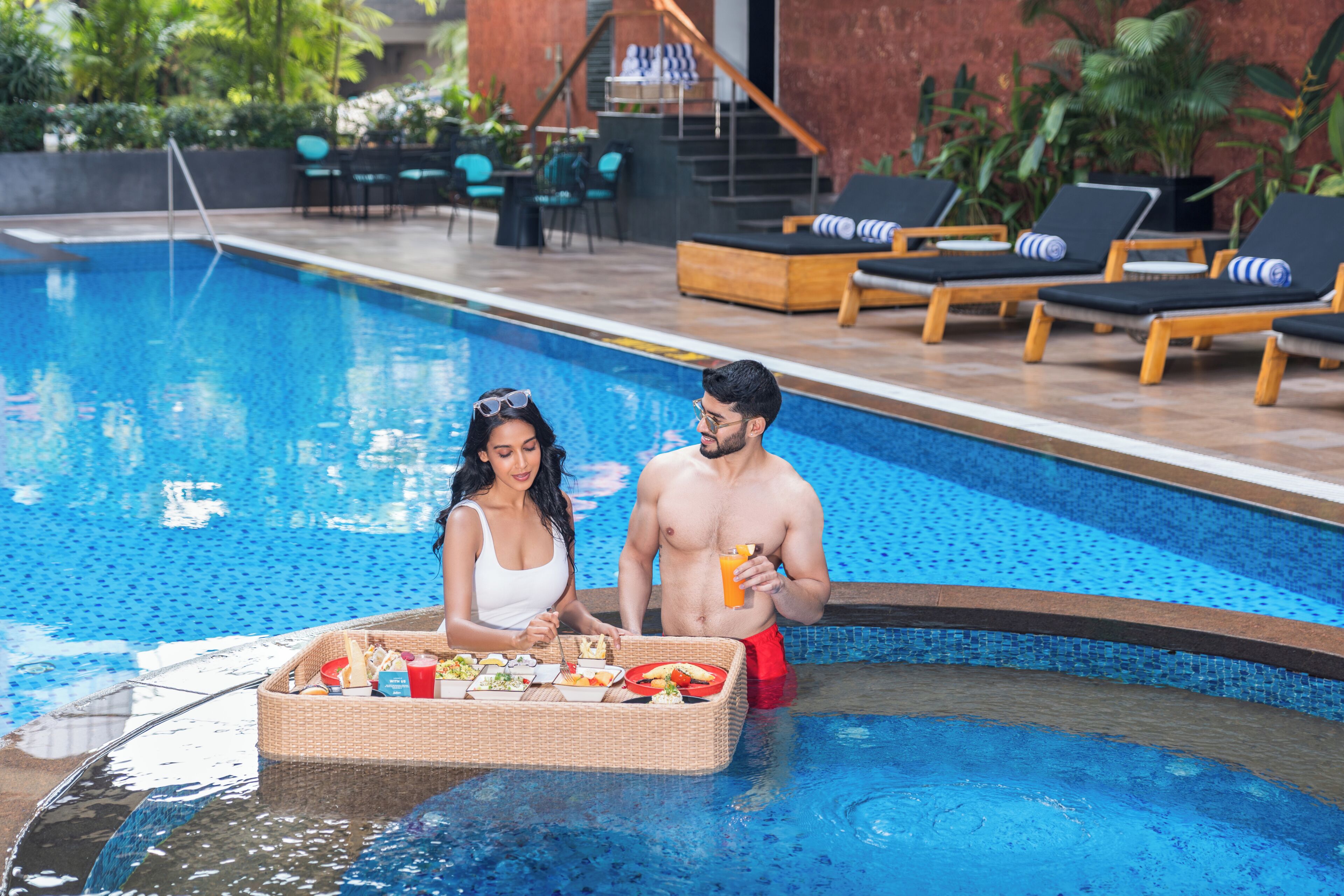 A swimming pool with lounge chairs and a wicker basket filled with food.