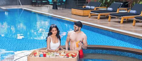 A swimming pool with lounge chairs and a wicker basket filled with food.