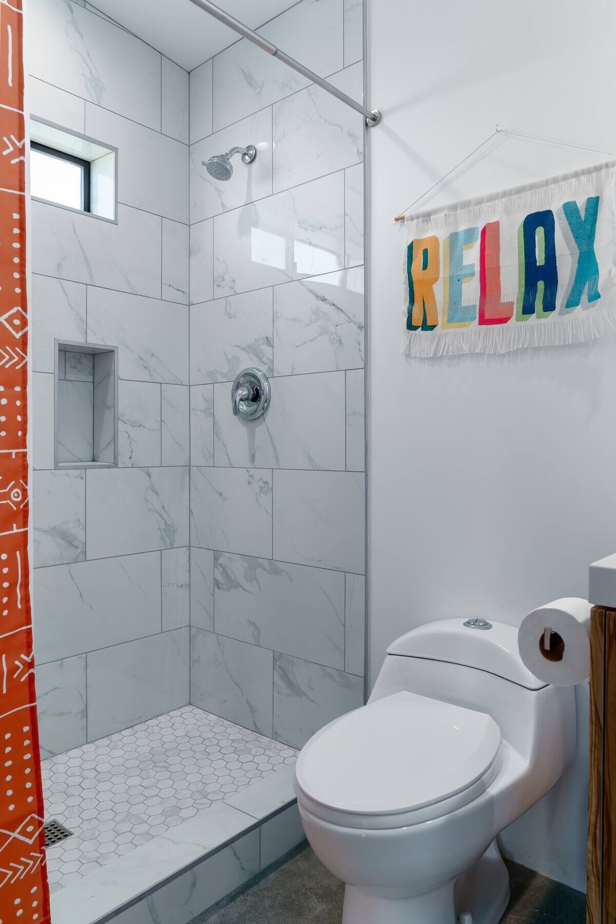 A modern bathroom with a shower, toilet, and a towel rack with a 'RELAX' sign.