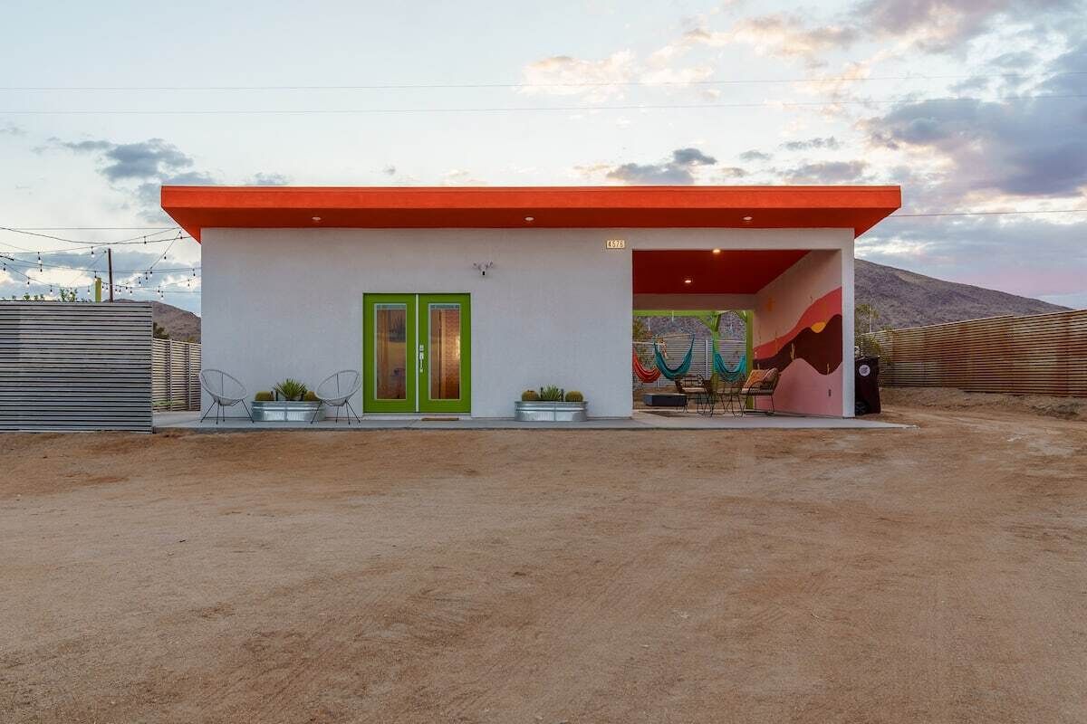 Un bâtiment moderne avec un toit rouge, des portes vertes et une fresque colorée à l’intérieur.