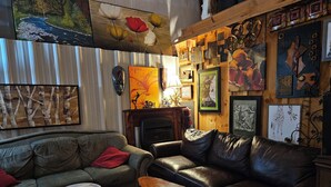 Ein gemütliches Wohnzimmer mit Kamin, Ledersofas und verschiedenen gerahmten Kunstwerken an den Wänden.
