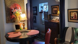 Ein Zimmer mit einem runden Tisch, Stühlen, einer Lampe, einem Ziertegels und einem Fenster mit Vorhängen.