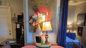 Ein Essbereich mit einem runden Tisch, zwei Stühlen, einer Blumenvase, einer Lampe und einem Bild an der Wand.