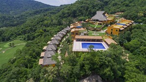 A resort with a swimming pool, thatched-roof buildings, and lush greenery. - El Corazón Golf & Spa Resort Manzanillo (Manzanillo)