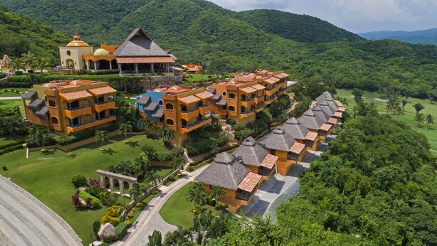 A resort with multiple buildings featuring thatched roofs, surrounded by lush greenery and hills. - El Corazón Golf & Spa Resort Manzanillo (Manzanillo)