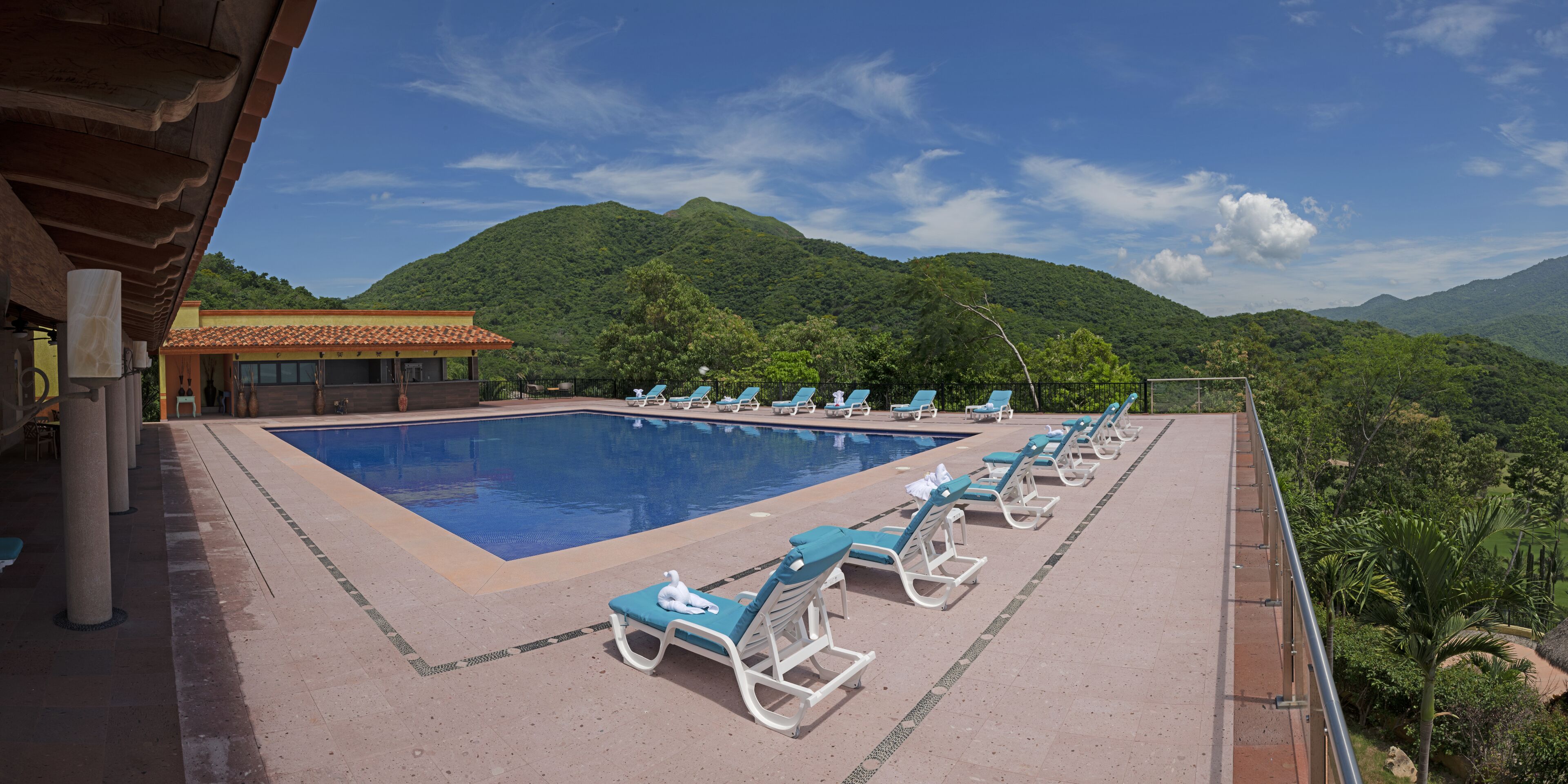 A pool area with lounge chairs and a view of mountains.