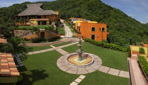 A resort with a central fountain, a well-maintained lawn, and buildings with thatched roofs. - El Corazón Golf & Spa Resort Manzanillo (Manzanillo)