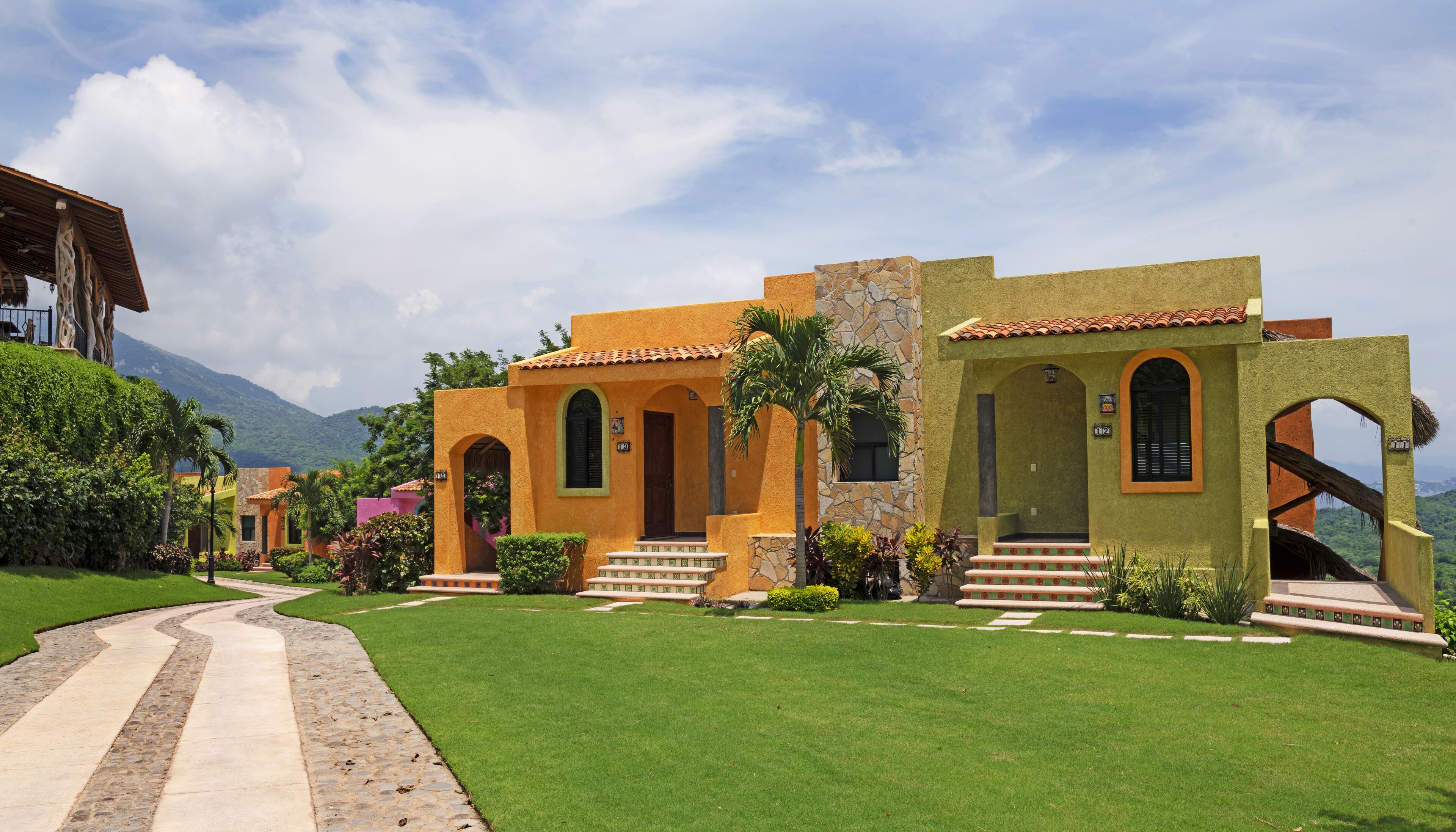 A building with a stone facade, arched doorways, and a well-maintained lawn.