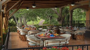 An outdoor patio with wicker furniture, tables, and chairs, surrounded by a black wrought iron railing. - El Corazón Golf & Spa Resort Manzanillo (Manzanillo)