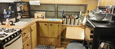 A compact kitchen with wooden cabinets, a gas stove, a sink, and various kitchen utensils.