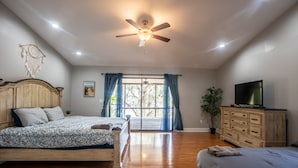 Une chambre à coucher avec un lit en bois, une commode, un téléviseur et un ventilateur de plafond.
