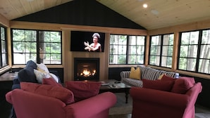 A cozy living room with a fireplace, comfortable seating, and large windows. - A Hidden Gem with Sandy Shore Memories and Island Views. (Township of Muskoka Lakes)