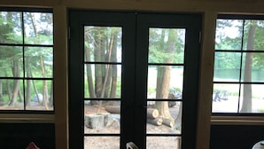 A room with a large window overlooking a forested area. - A Hidden Gem with Sandy Shore Memories and Island Views. (Township of Muskoka Lakes)