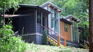 Eine moderne Holzhütte mit großen Fenstern und einer Holztreppe zum Eingang.