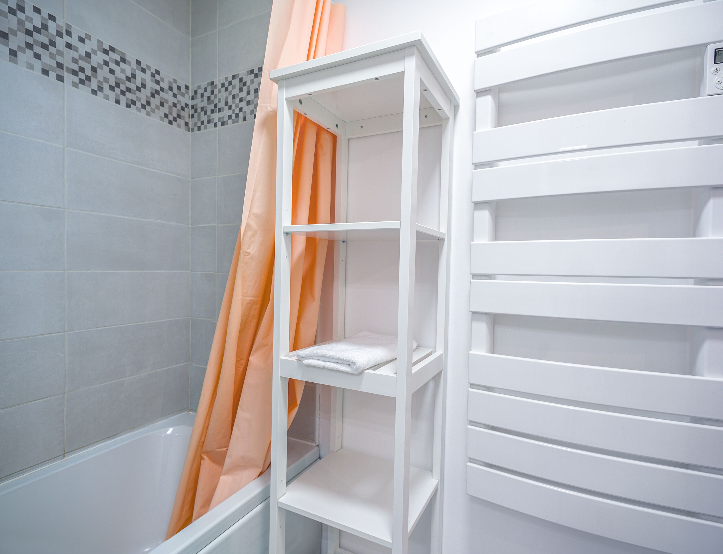 Ein Badezimmer mit einer weißen Badewanne, einer Duschvorhang und einem weißen Regal.