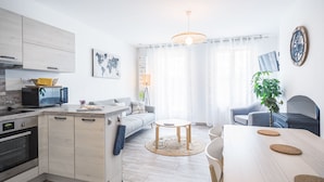 A modern kitchen with a microwave, oven, and a sink. There is a dining area with a table and chairs, a sofa, and a potted plant. - Le Duplex du Lac d'Orient #3 - Near the lake (Mesnil-Saint-Père)