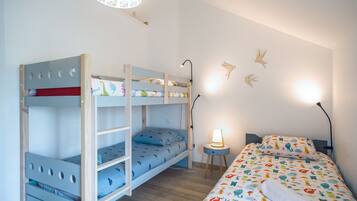 Cozy bedroom with a bunk bed and single bed, featuring a bedside table and lamp.