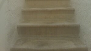 A narrow, dimly lit stairway with a rough wall texture and a light at the top. - Period house in the murattiano suburb- CIS: BA07203091000021052 (Monopoli)